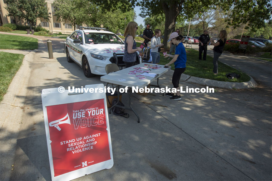 Students sign a "Use Your Voice" pledge and affix them to a police car during the September 10 Cover the Cruiser event on East Campus. More than 75 students, faculty and staff made a pledge to stand up to sexual violence in the first day of the initiative. The Cover the Cruiser events continue Sept. 12 and 13. Both events are 10:30 a.m. to 2 p.m. on the Nebraska Union Plaza. September 10, 2019. Photo by Troy Fedderson / University Communication